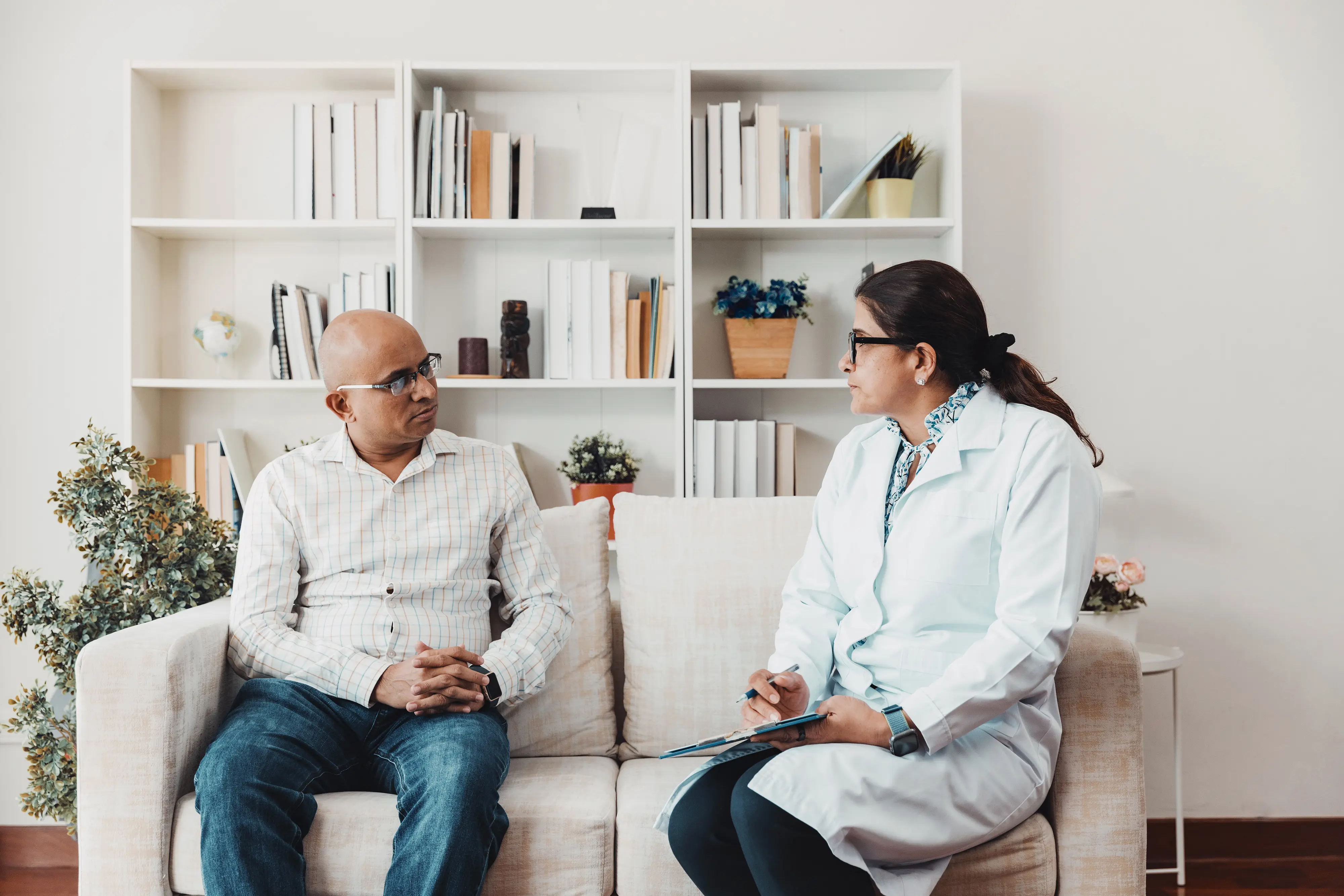 Doctor and patient talking while sitting on a sofa in a bright modern office