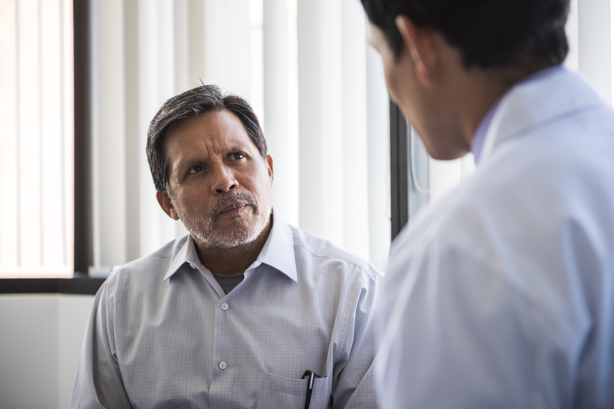 Male Patient Talking To Doctor In Hospital Room