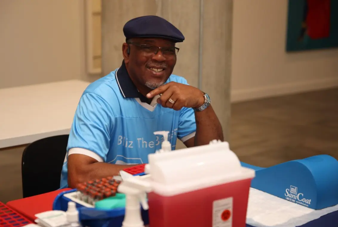 Volunteer at a check-in table working the Blitz the Barriers Screening Event. The event check-in took place in an indoor community setting.