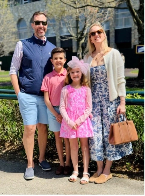 A family of four dressed in spring attire, standing together outdoors