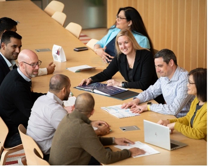 A group of men and women sitting around a conference table, actively participating in a discussion