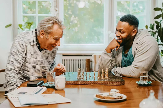 An older man playing chess with a younger man 