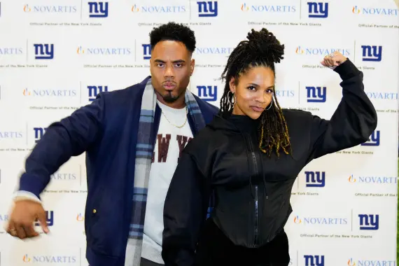 Two people posing in front of New York Giants background