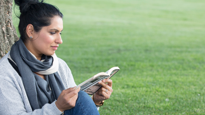 Woman relaxing under a tree reading a book