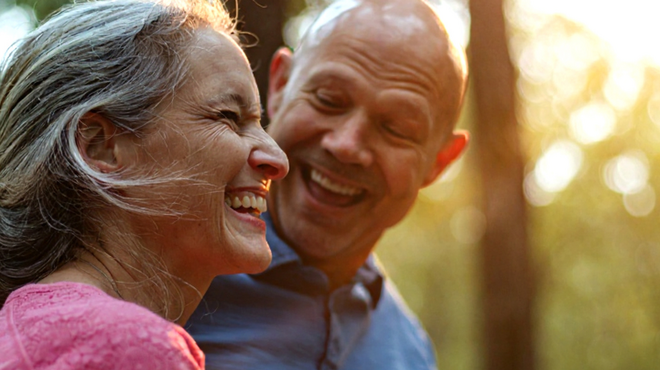 Elderly coupling hugging in sunlit forest